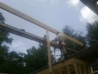 Carpenter setting a ridge beam over a new addition frame — Ice Dam Removal by Roofing Brothers in Miles
