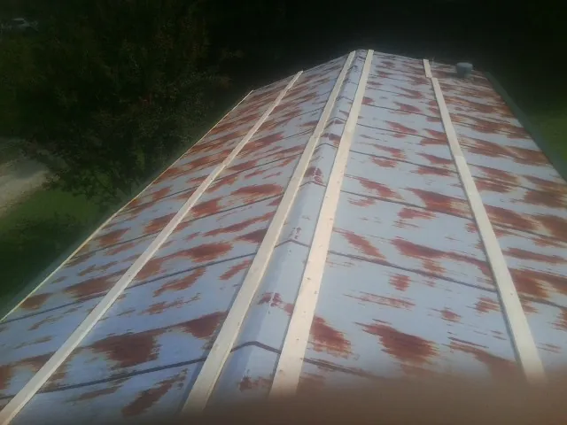 Rusted metal roof panels with new wood purlins before replacement — Storm Damage Roof Repair in Miles by Roofing Brothers