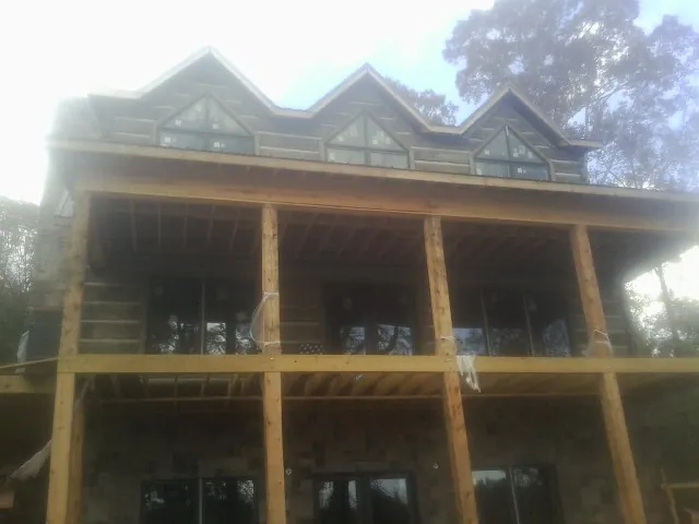 Dormers and porch framing on a large log home under construction — Roof Coating work by our crew in Miles