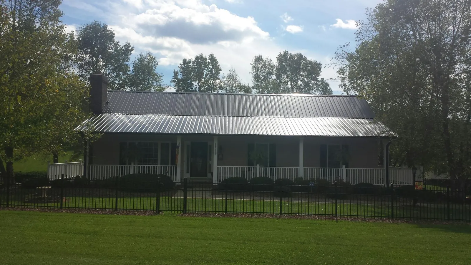 Gray metal roof on a brick ranch with a full width front porch — Gutter Guard Installation work by our crew in Miles