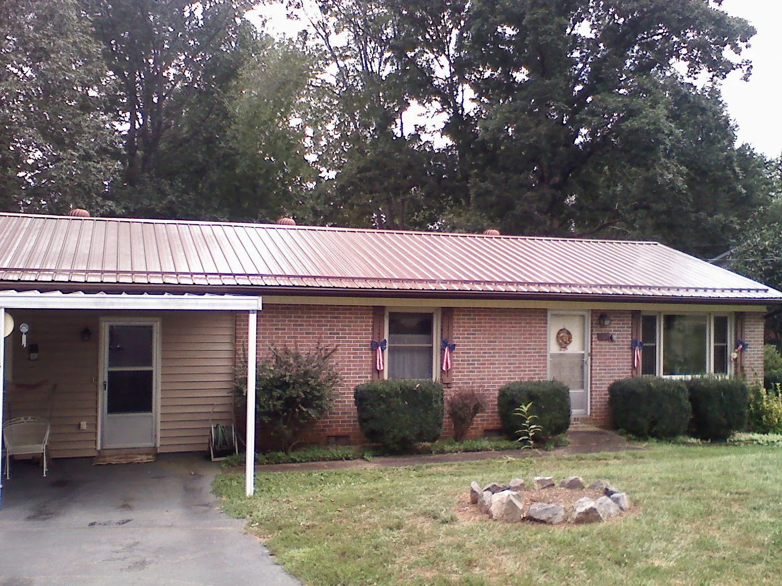 Bronze metal roof and carport on a brick ranch home — Roof Repair work by our crew in Miles